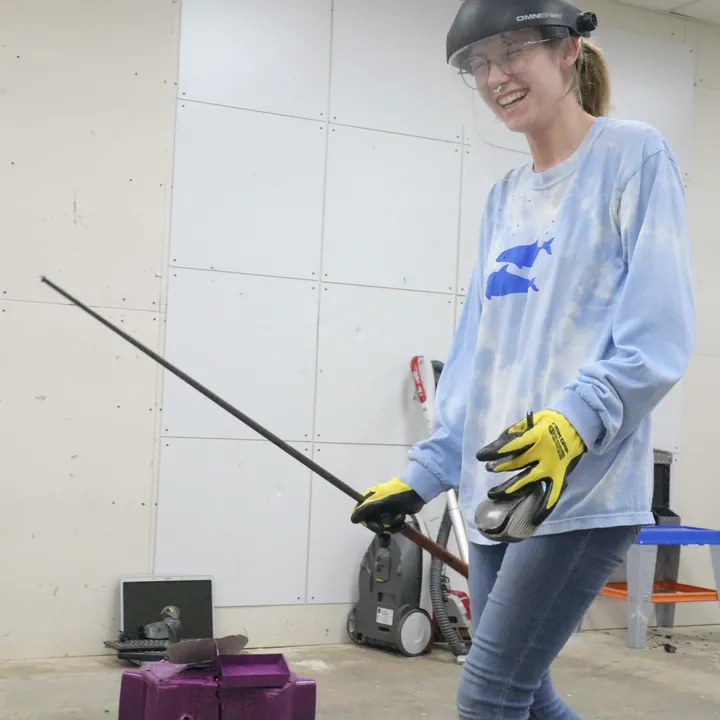 A guest smiling while smashing at The Smash Room Tulsa