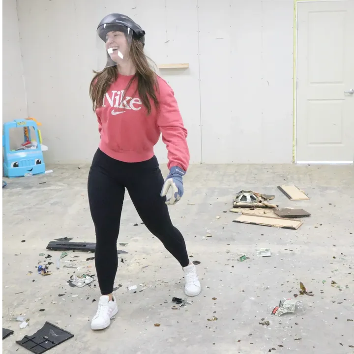 A guest celebrating among the debris in the rage room
